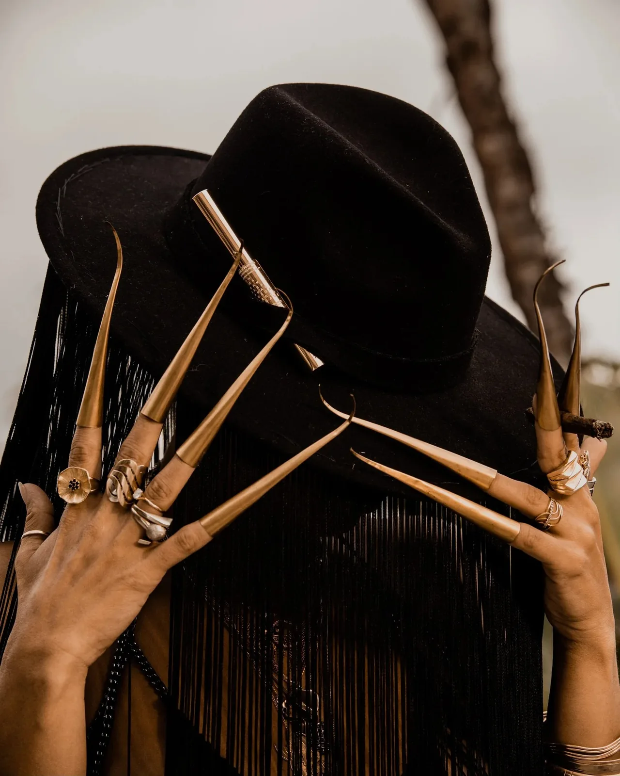 Ranagade in a black hat with long gold nail cuffs
